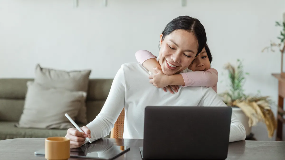 A child hugs a parent who is working from home