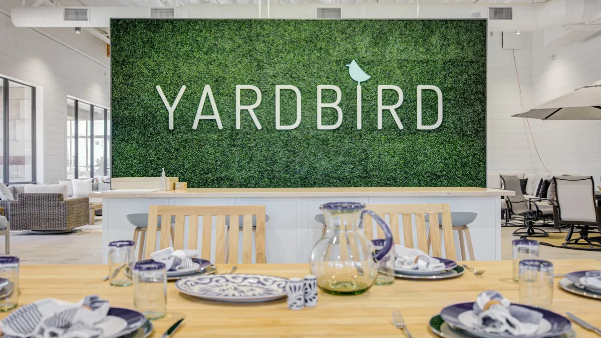 A wood table with dining plate son it underneath a sign saying Yardbird