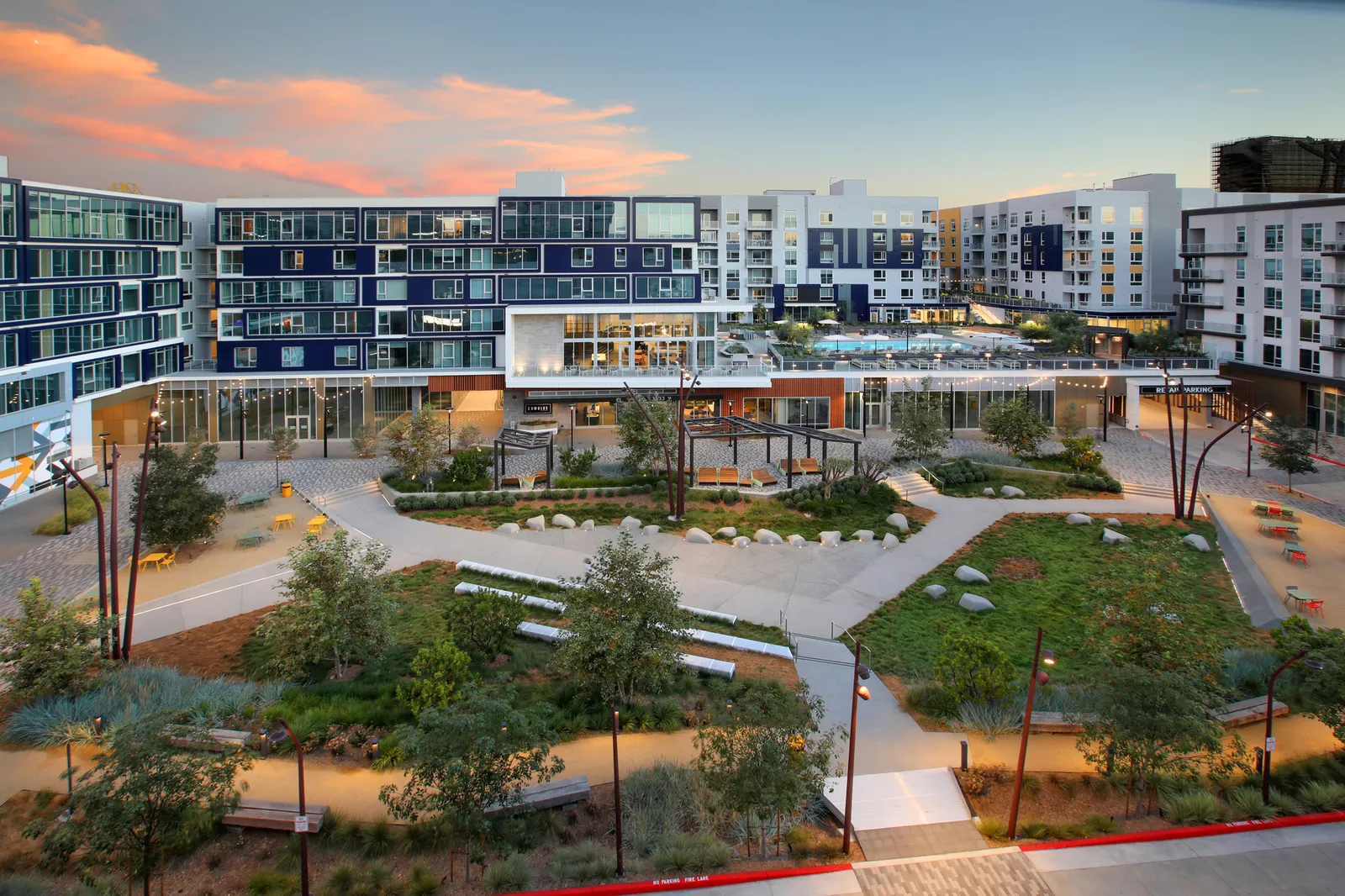 A blue, white and orange apartment building behind a large courtyard.