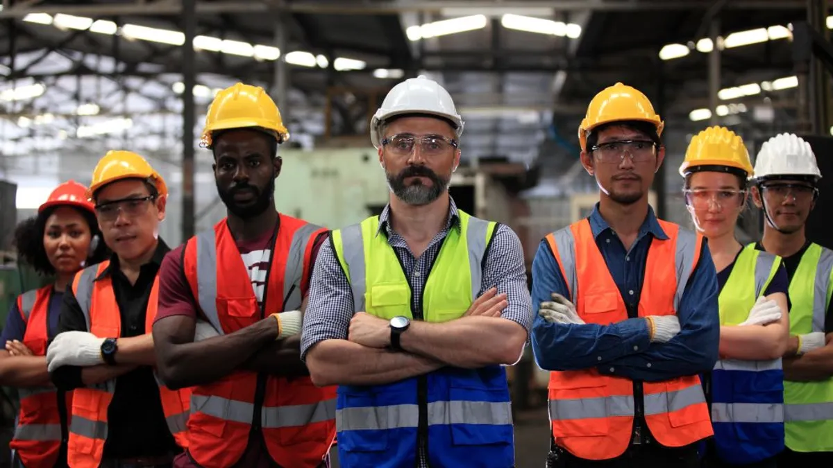 Team of engineers and factory workers standing crossed arms looking at the camera