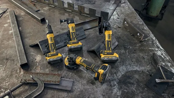 Four black and yellow grinder tools set on a dusty floorl