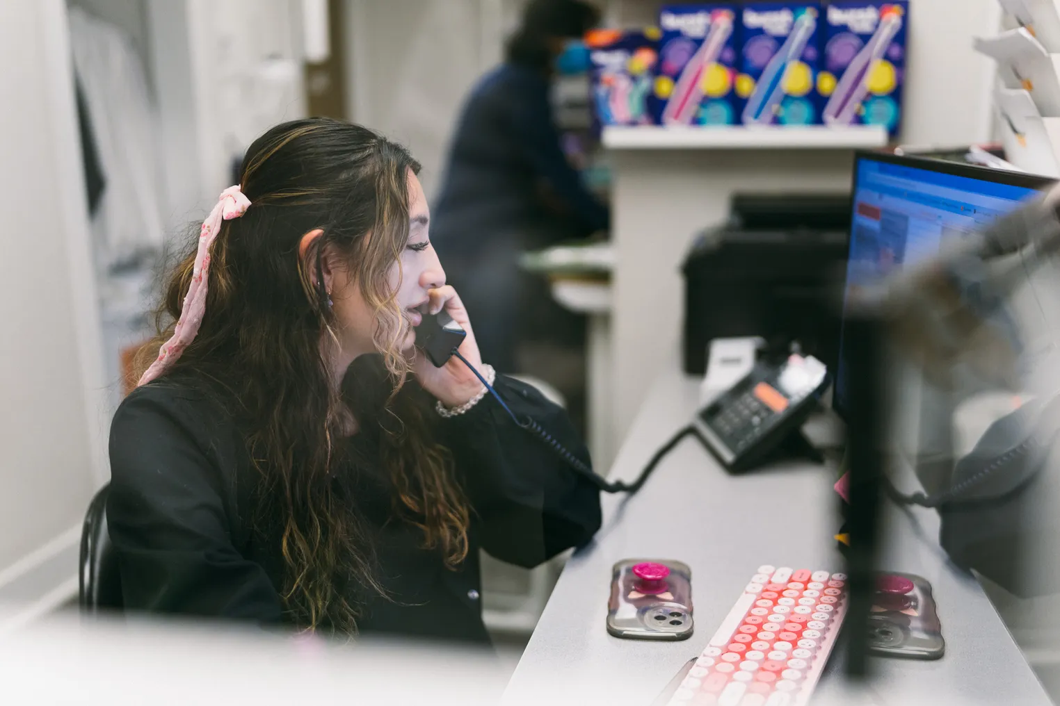 Secretary talks on the phone while working at her desk.