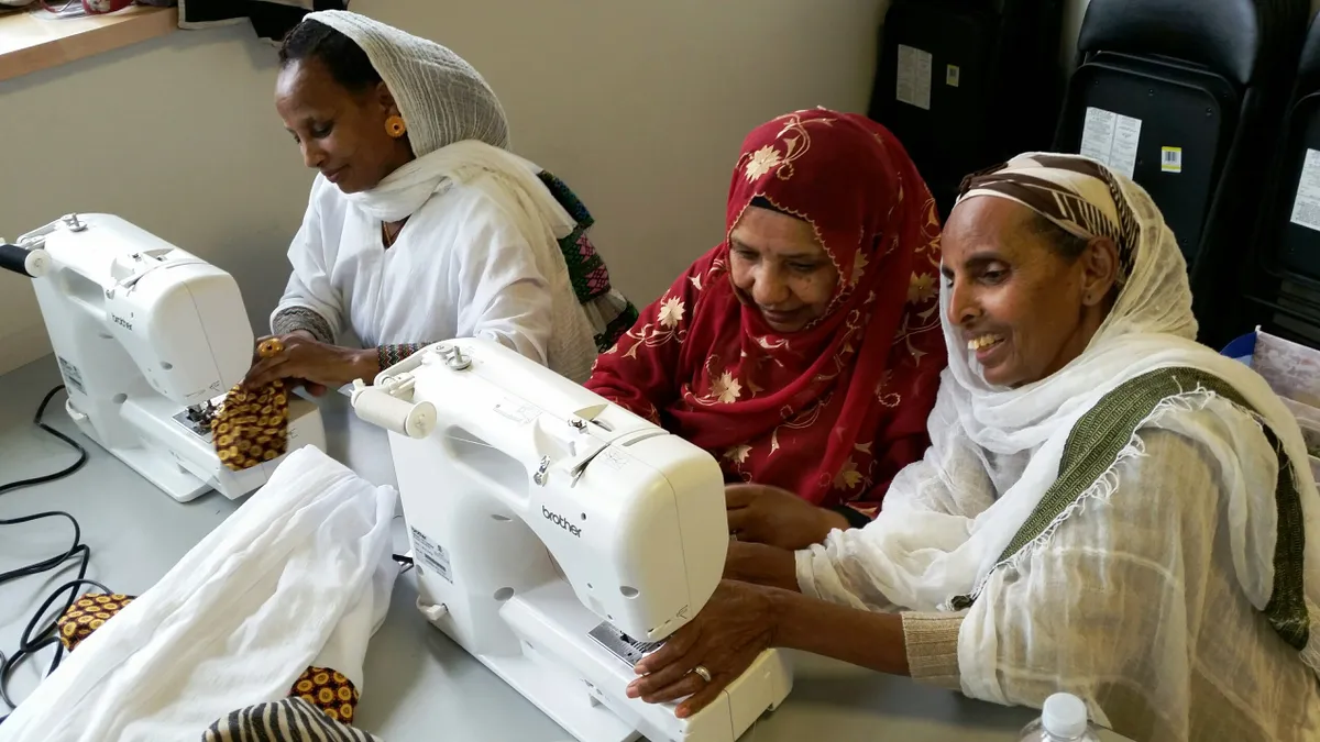 Residents in the Yesler Arts Program use sewing machines during a course introducing them to the professional garment industry.