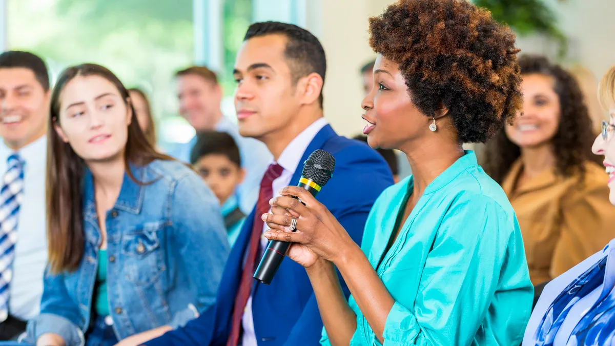 A woman asks a question during a public meeting.