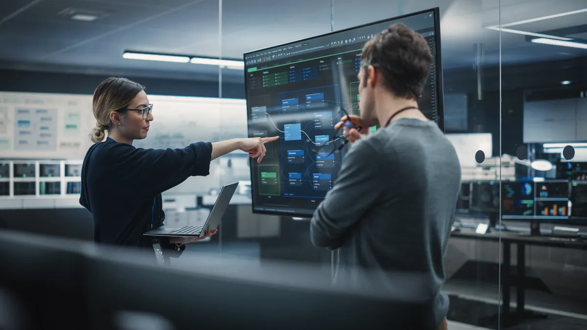 two technologists in front of a monitor at an office