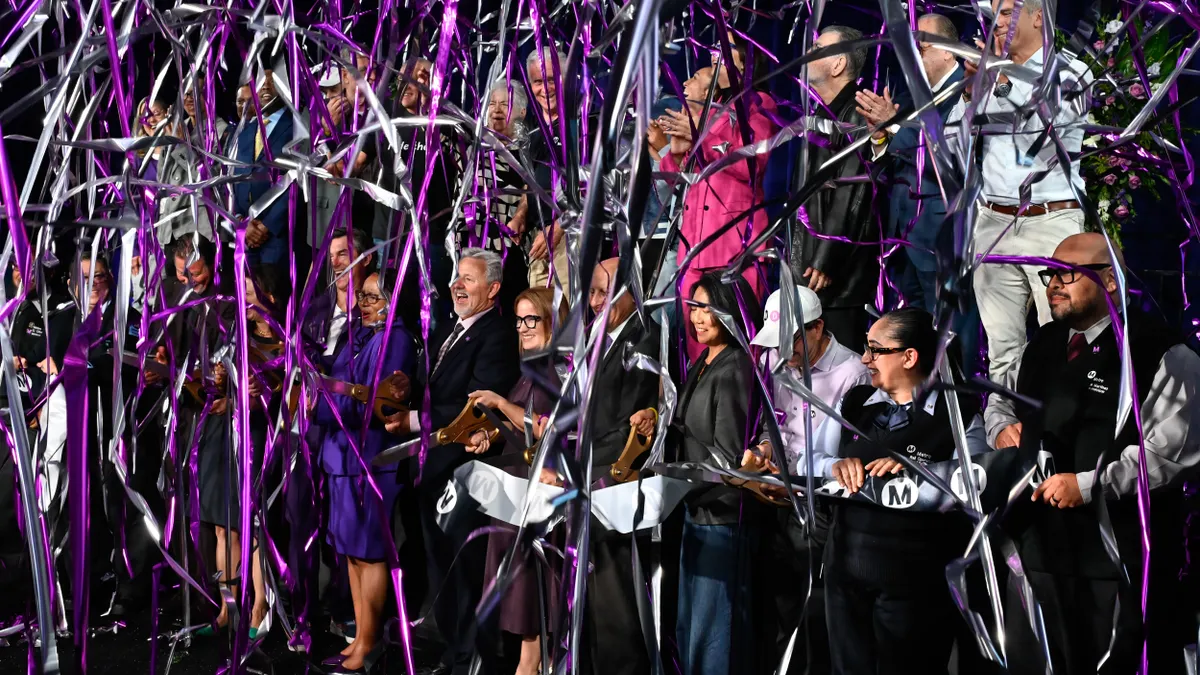 Multicolor ribbons of confetti rain down on people.