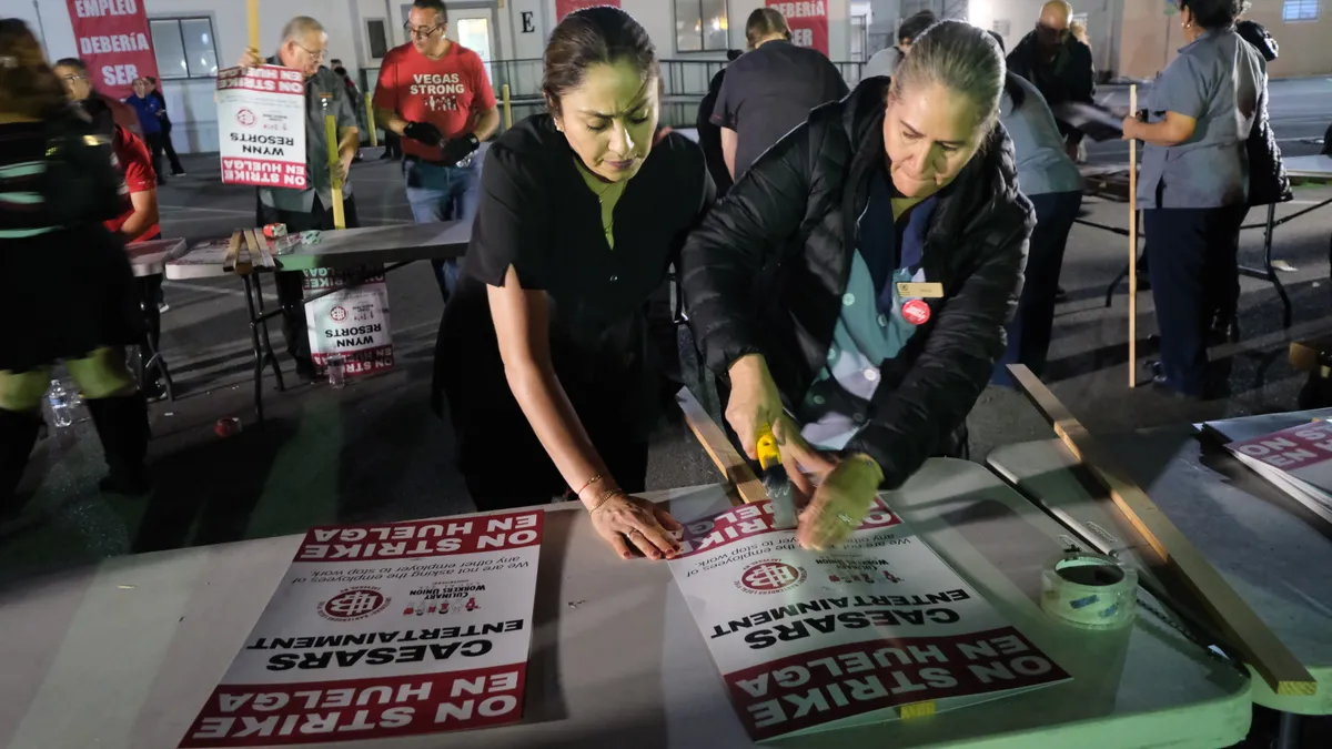 Two women put together signs that read "ON STRIKE."