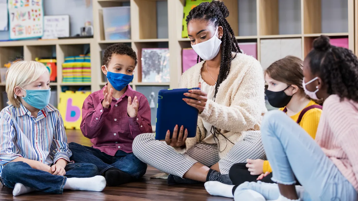 Preschool teacher, students in class, wearing masks - stock photo