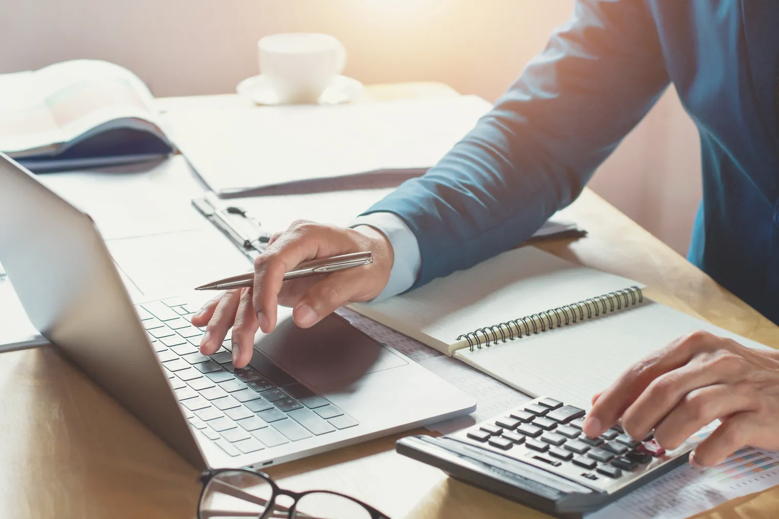 Businessman working in office using calculator and laptop.