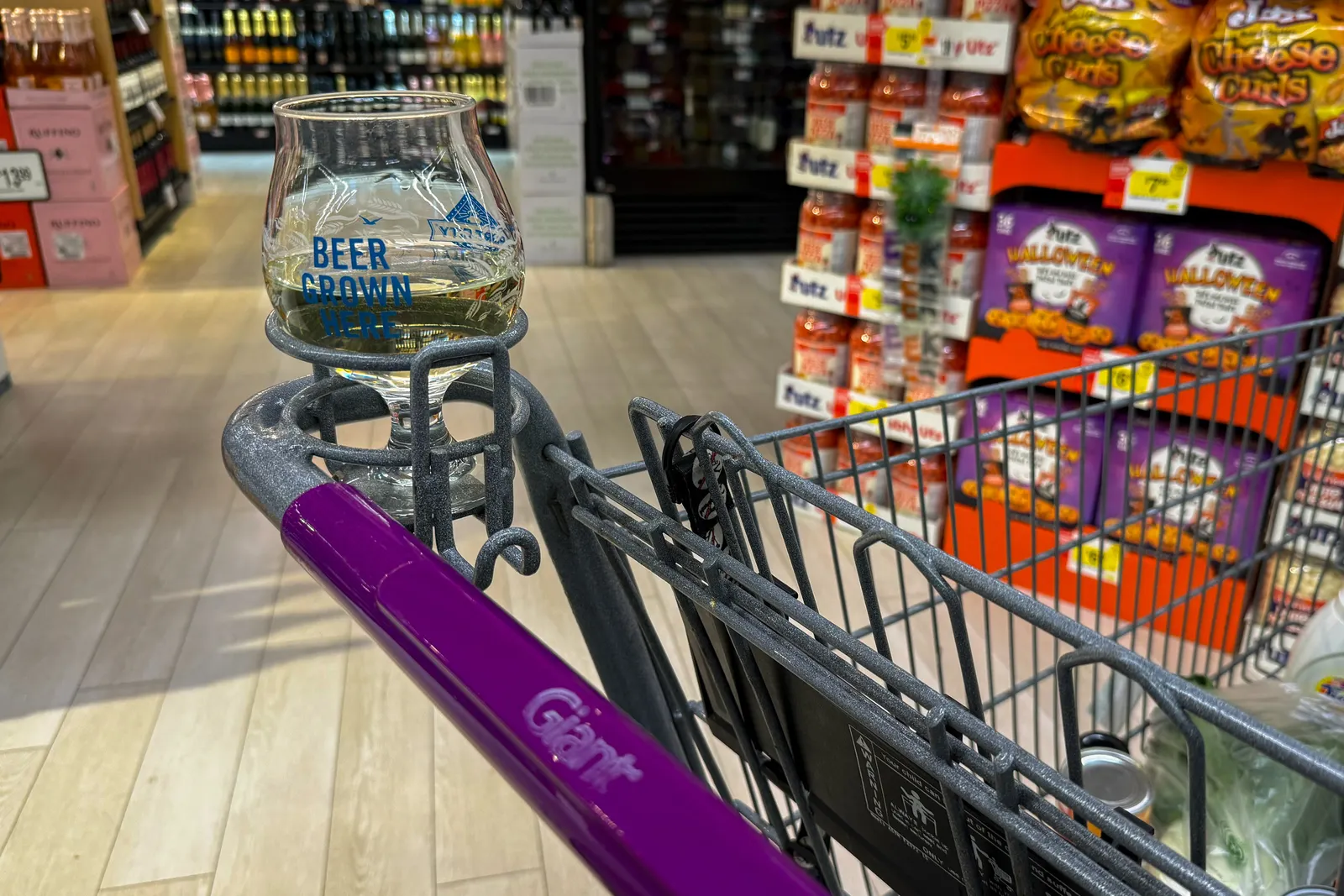 A glass of alcohol in a grocery cart cupholder.