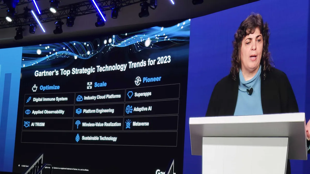 A woman is depicted on a big screen next to a slide with 10 tech trends shown.