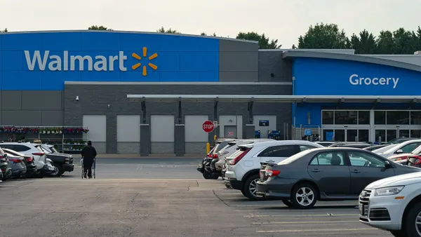 Exterior of Walmart store with a sign that reads "grocery" and two cars parked in front.