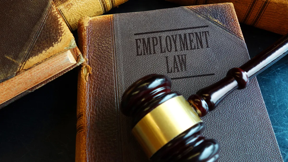 A brown worn employment law book with brown and shiny legal gavel on top of it.