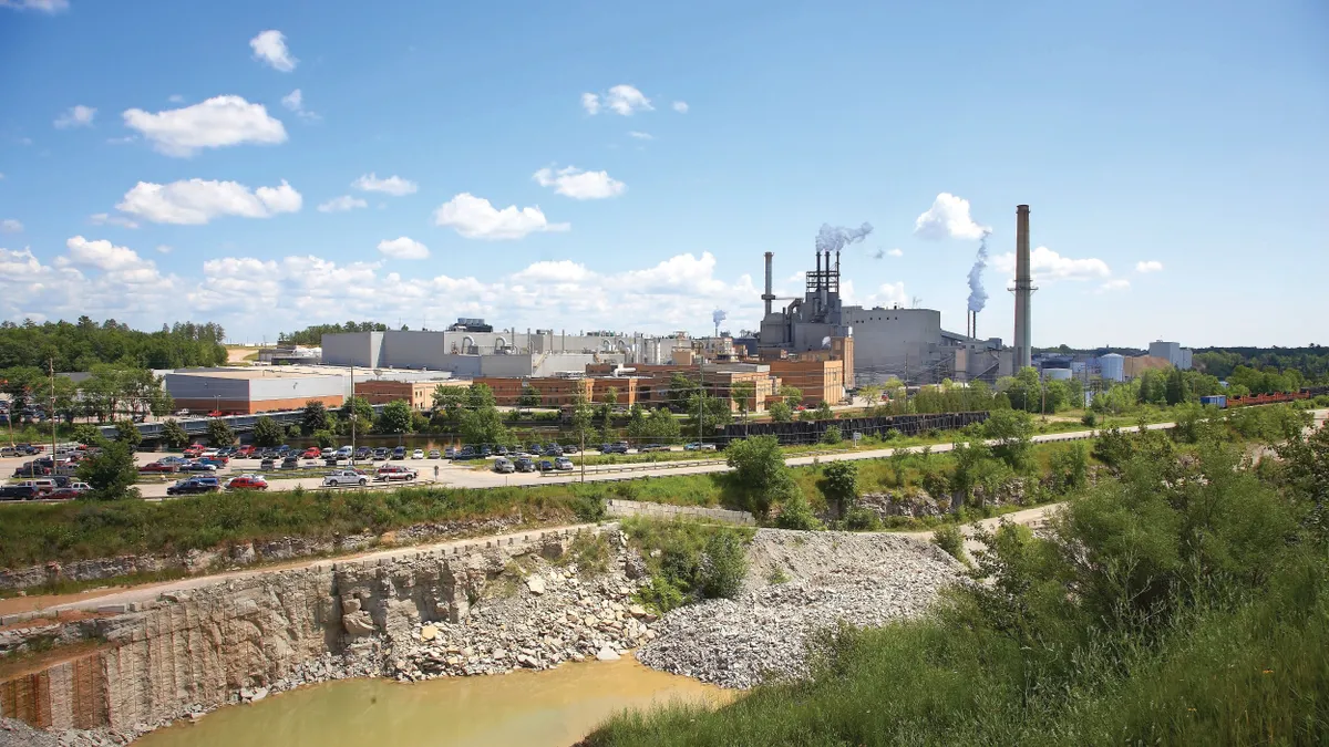 A wide shot of an industrial facility with smoke emerging from smokestacks.