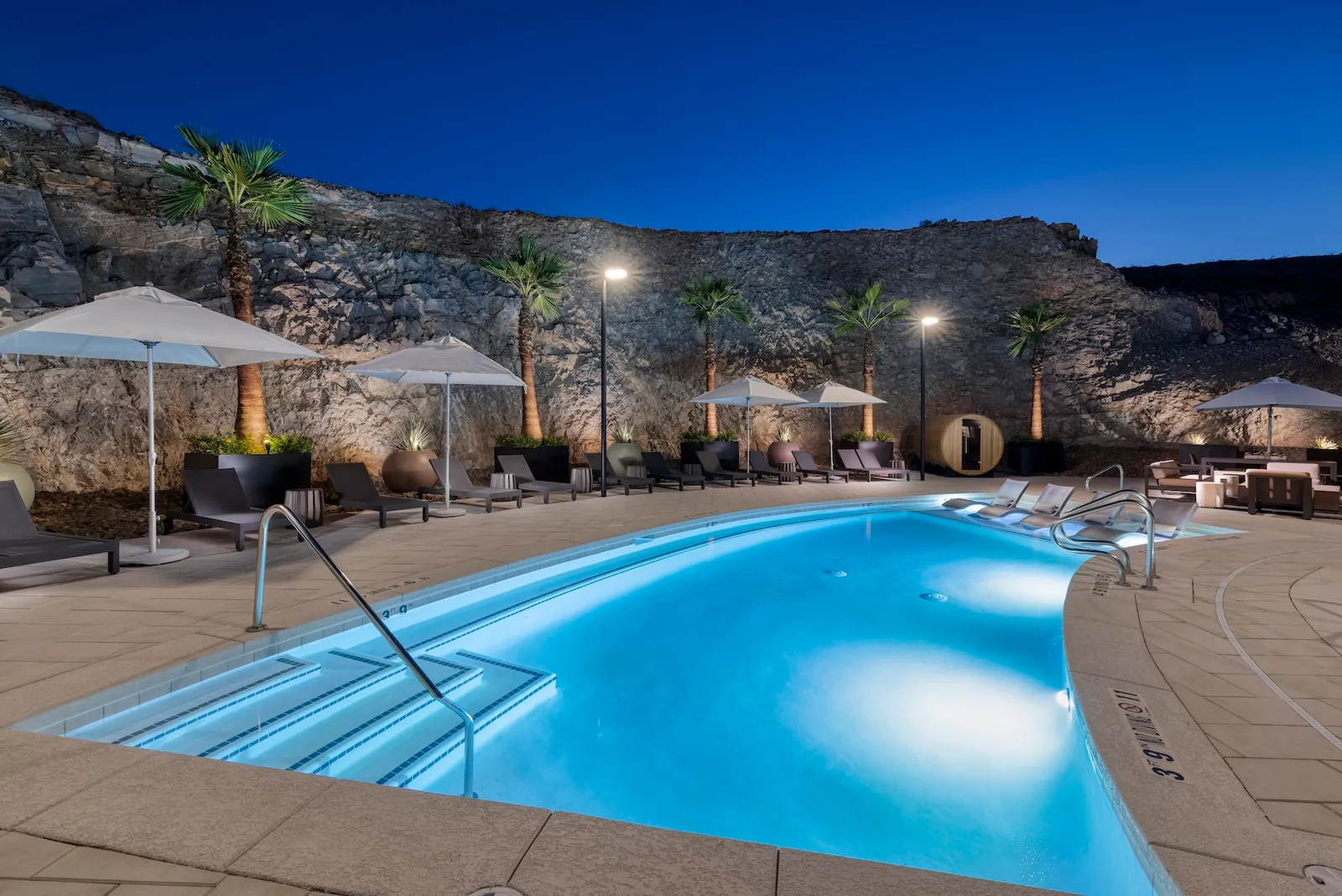 A pool and some chairs in the side of a mouintain.