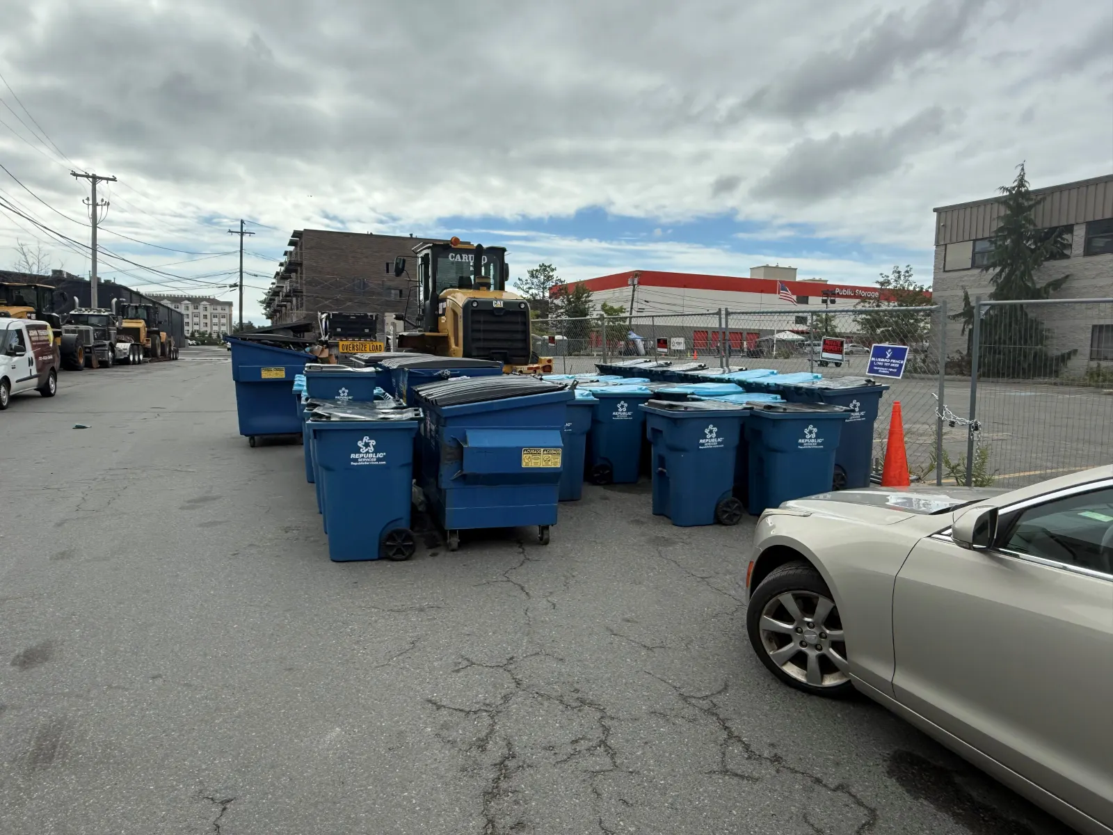 Several dumpsters and bins sit in a concrete yard