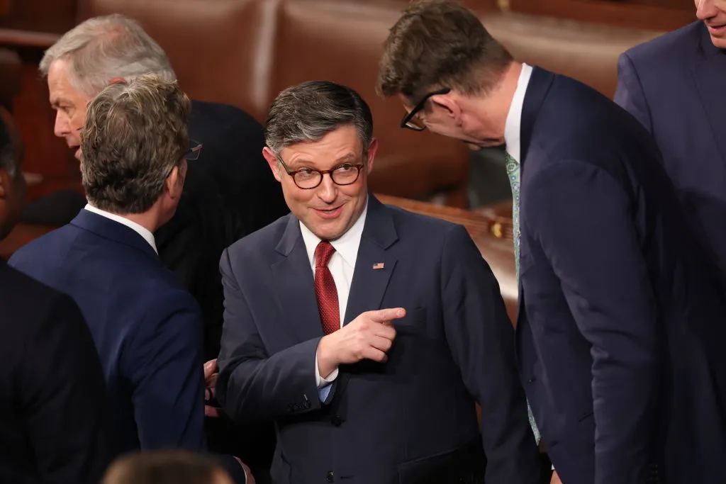 Mike Johnson chats with fellow Republicans in the House Chamber of the U.S. Capitol.