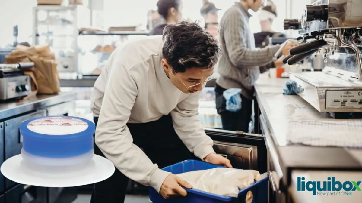 A person handles a bag of milk next to an espresso machine.