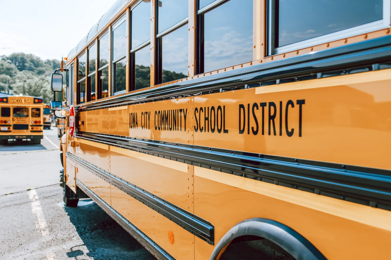 A view of the left side of a yellow school bus that reads "Iowa City Community School District."