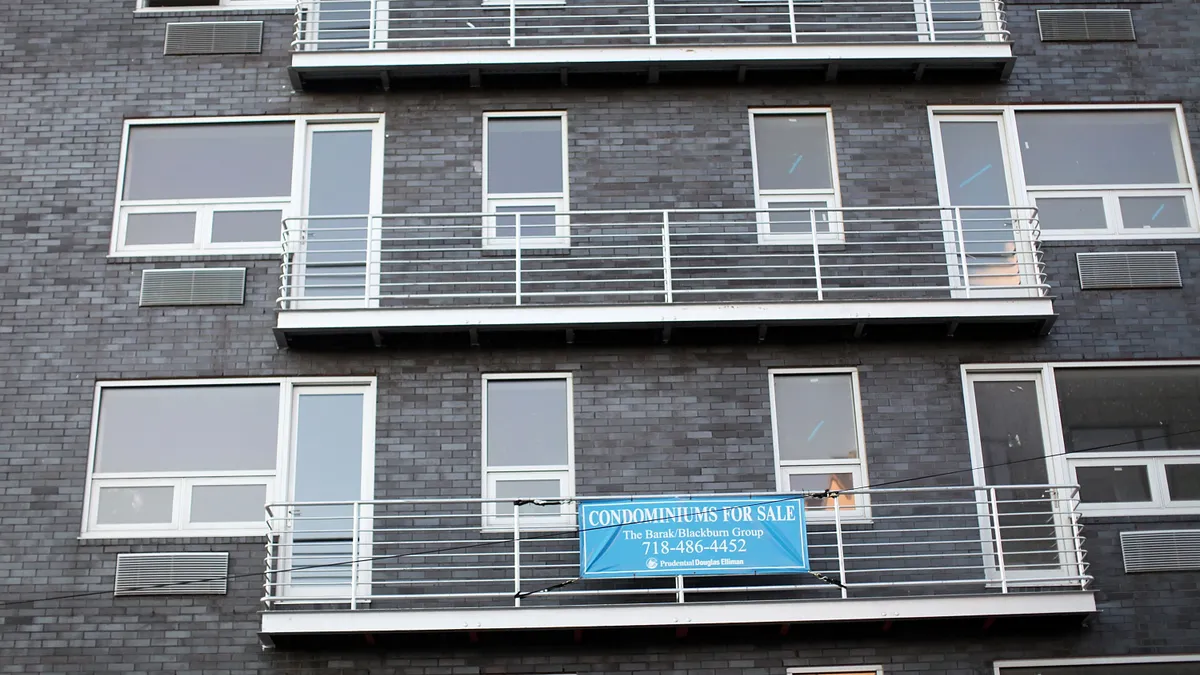 The side of gray apartment building with white railing.