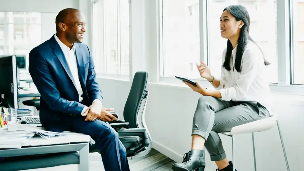 Smiling businessman and businesswoman discussing project at office workstation