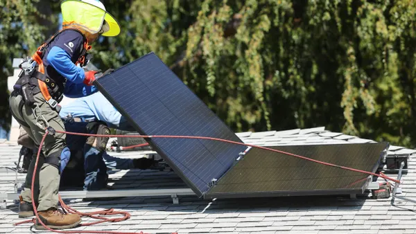 A worker installs a solar panel on a home.