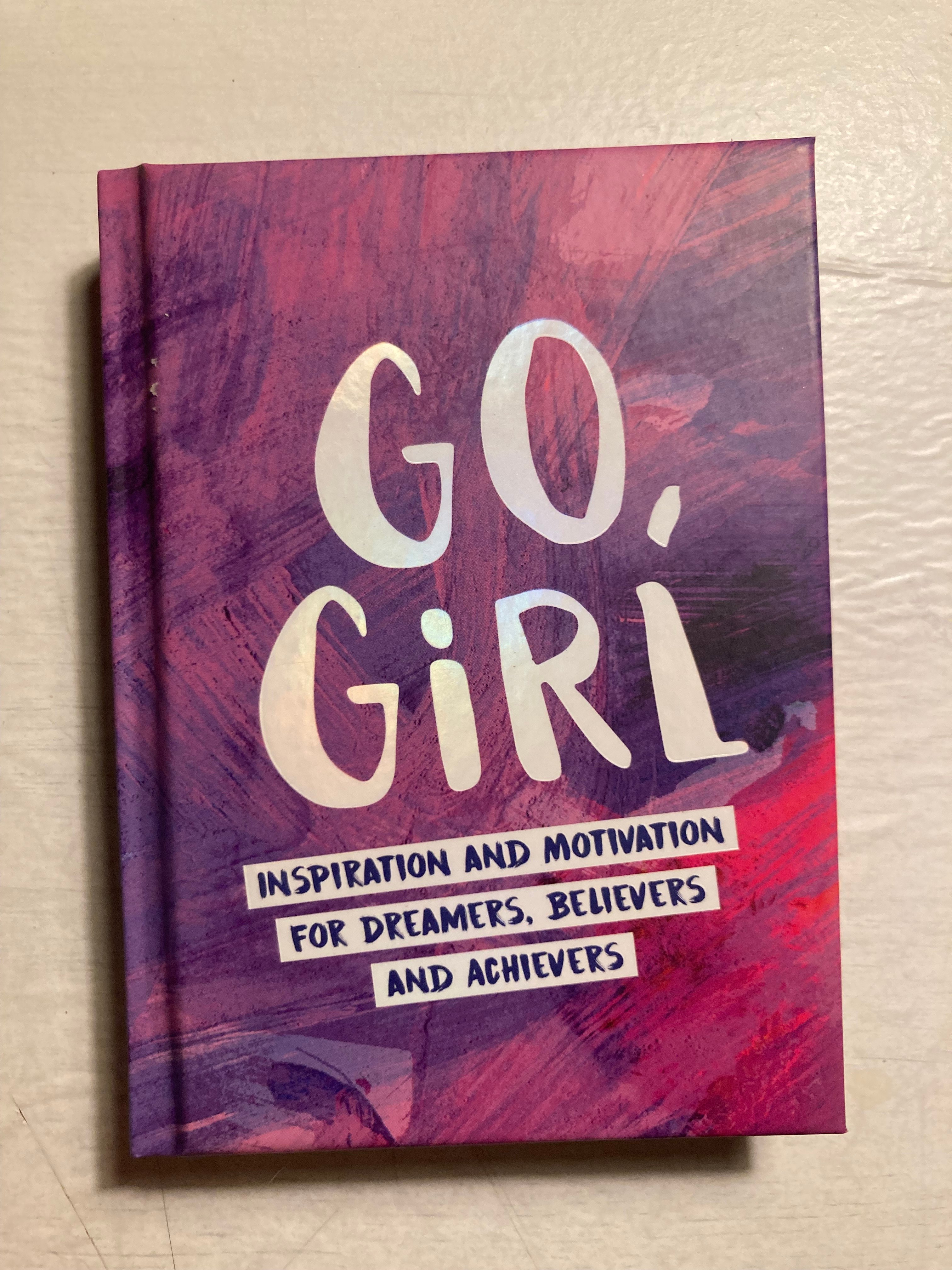 A purple and pink book reads "Go, girl: Inspiration and motivation for dreamers, believers and achievers"