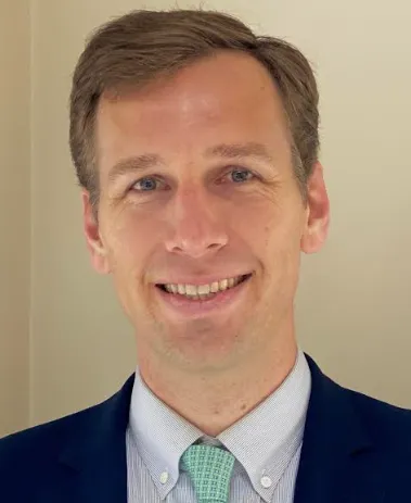 Headshot of a man in dark suit and green tie