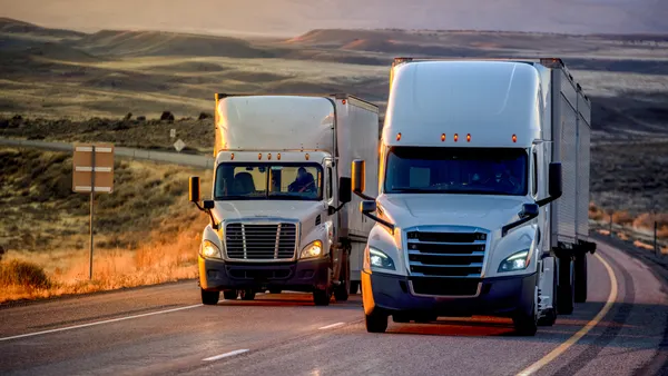 Trucks on a highway with plateaus and mountains in the background.