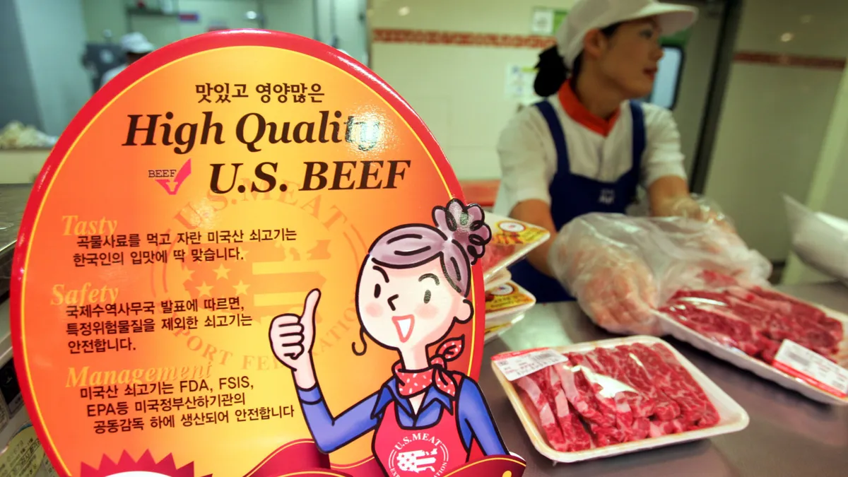 An employee prepares puts beef in packaging at a store. A nearby sign promotes U.S. imported beef.