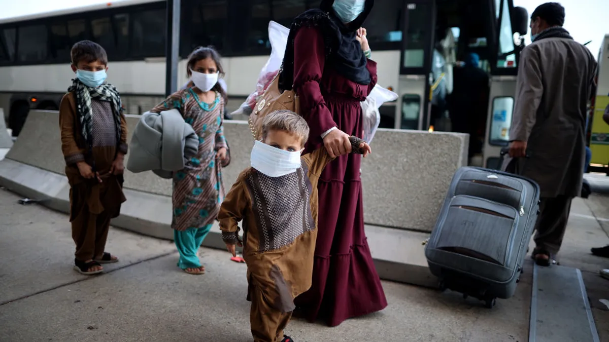 Refugees board buses that will take them to a processing center at Dulles International Airport after being evacuated from Kabul following the Taliban takeover of Afghanistan August 27, 2021.