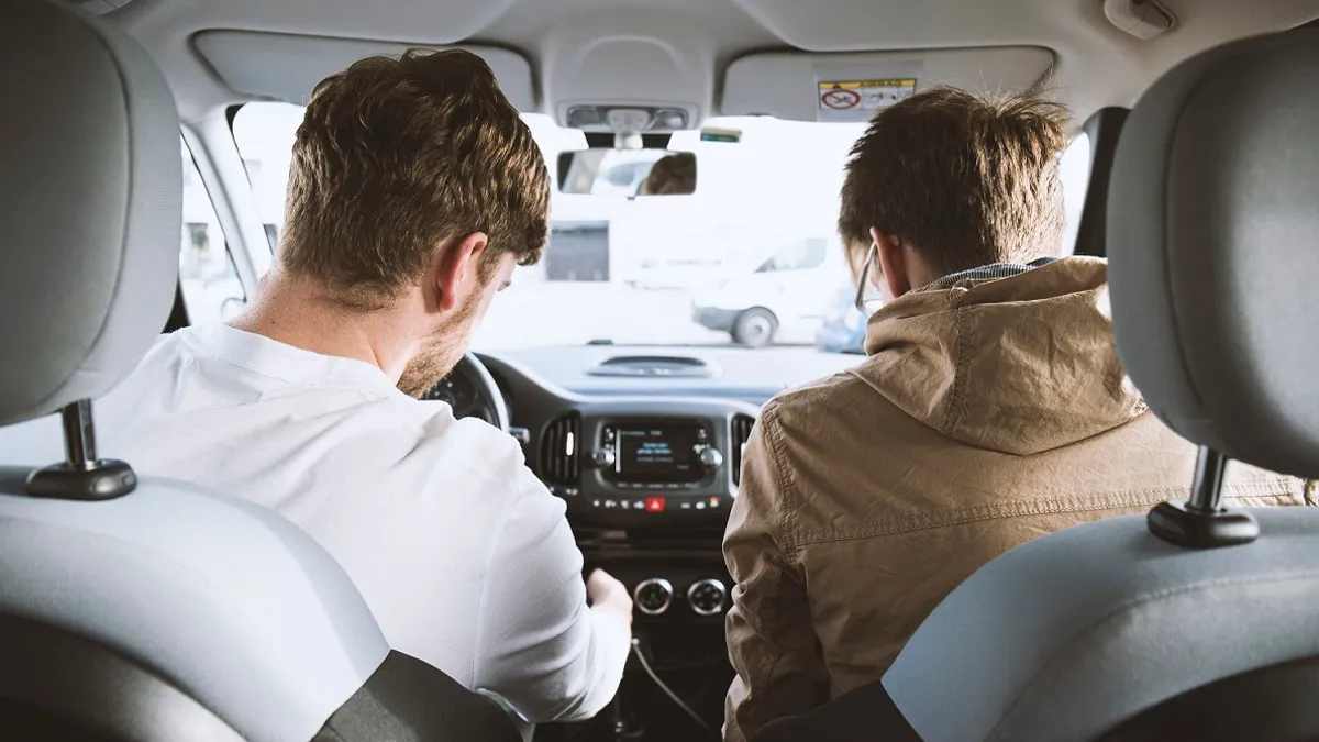 Rear view of two individuals sitting in a car.