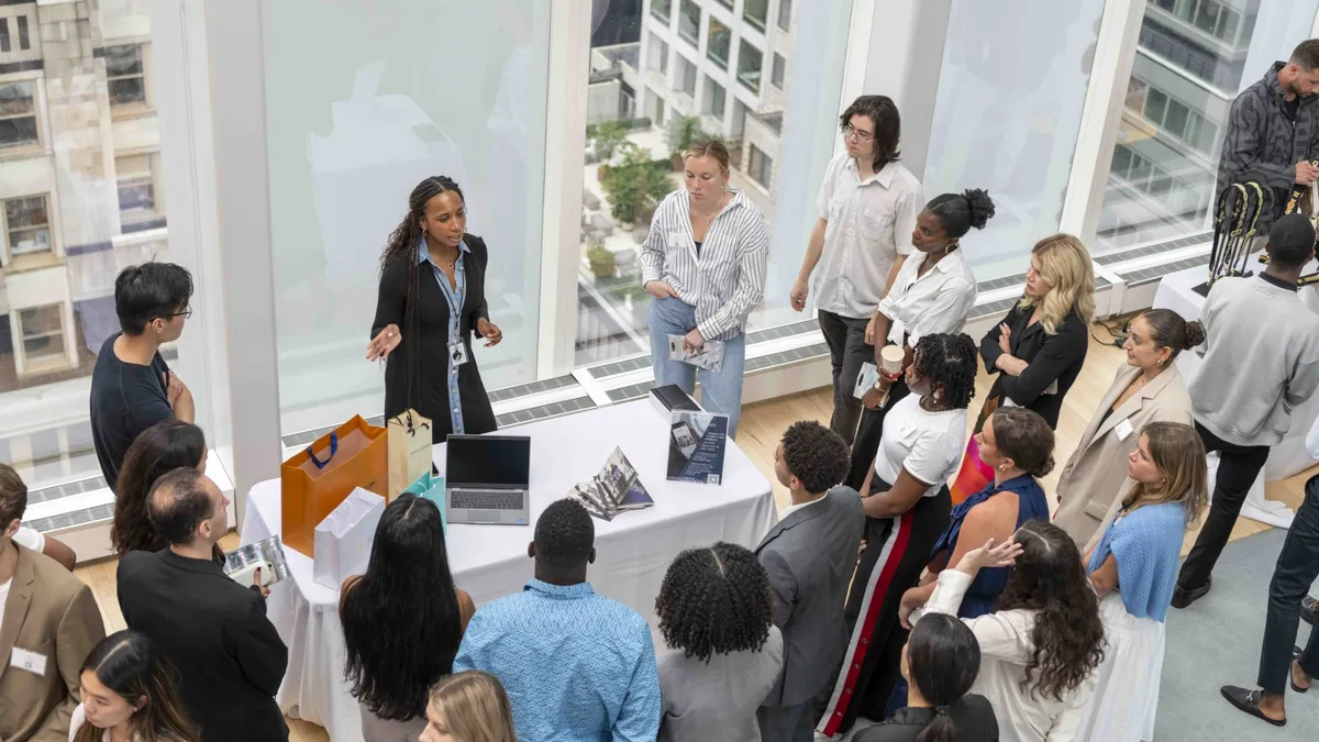 An individual speaks to others, with LMVH branded bags displayed on a table.