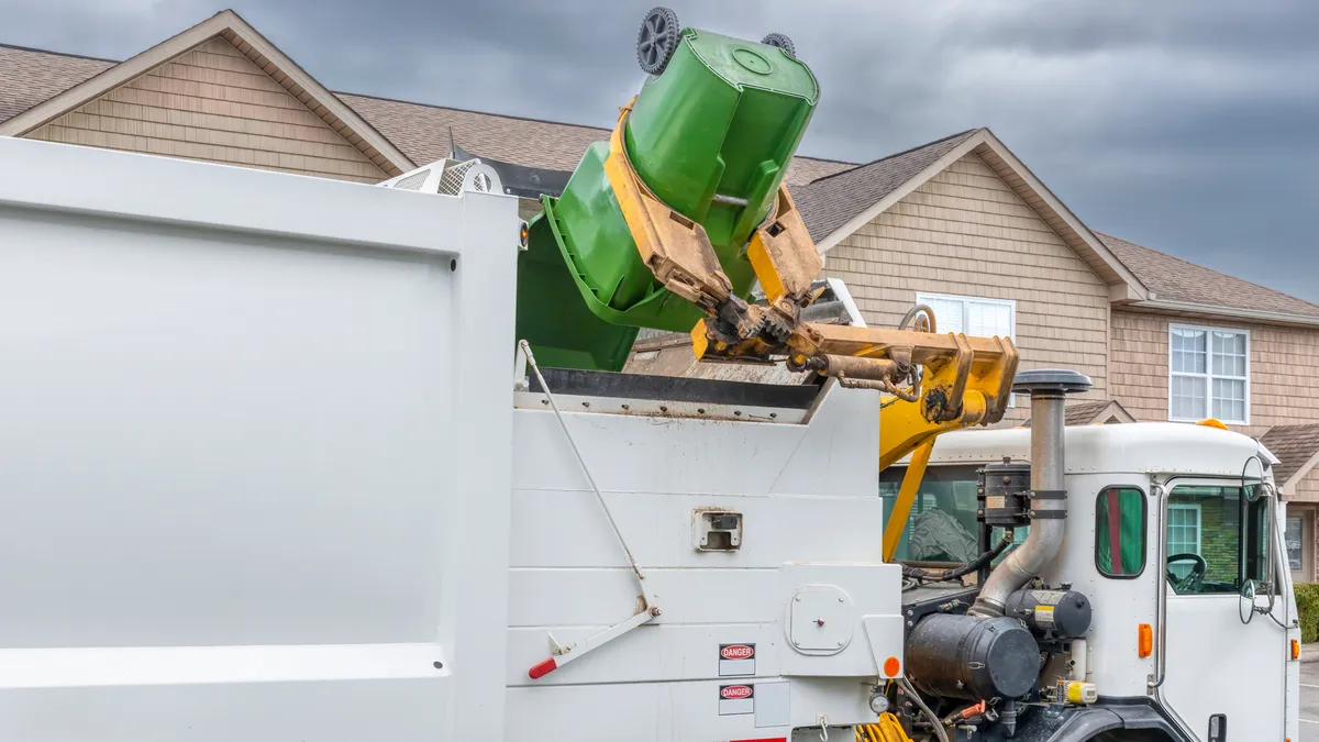 Waste collection truck with an automatic sideloader