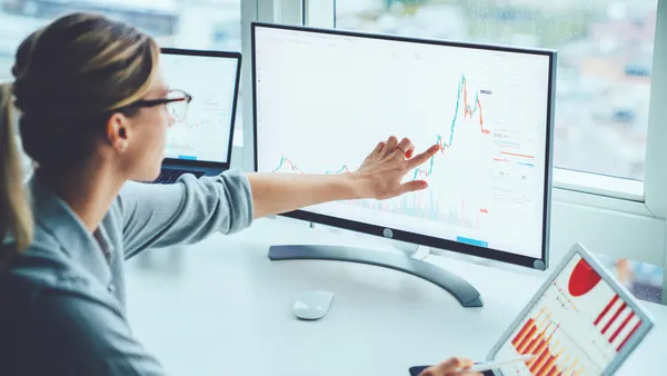 Business woman studying financial data on computer screen.