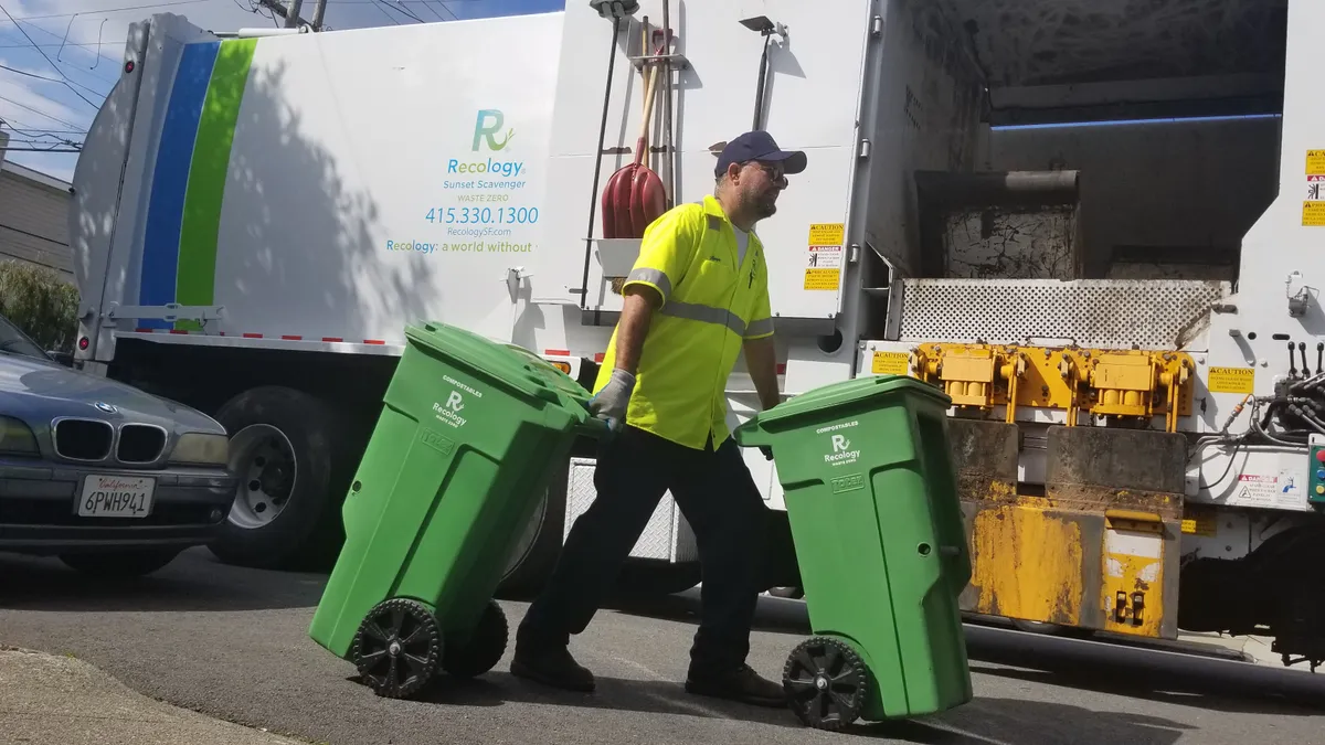 A Recology employee collects green curbside compostable material bins.