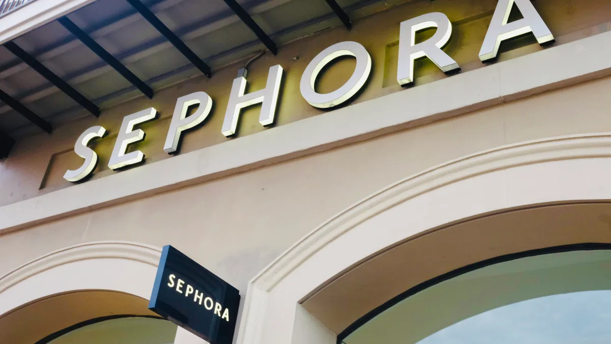 A lit-up "Sephora" sign in white letters, with a small black "Sephora" sign jutting out below.