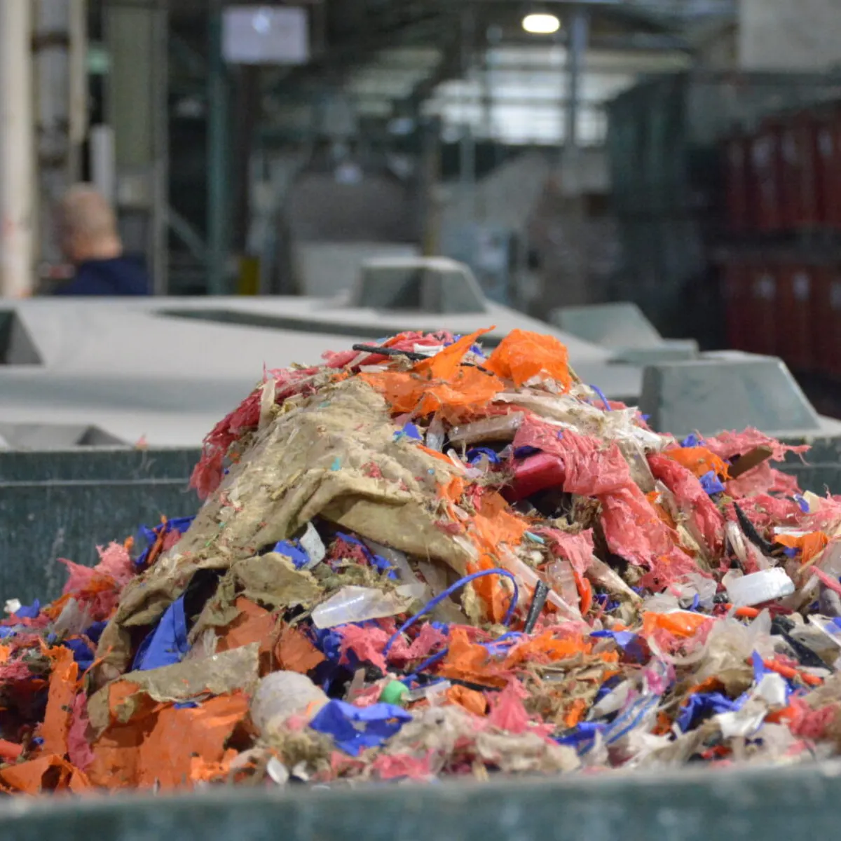 A pile of mixed plastic scrap of varying colors inside an industrial facility