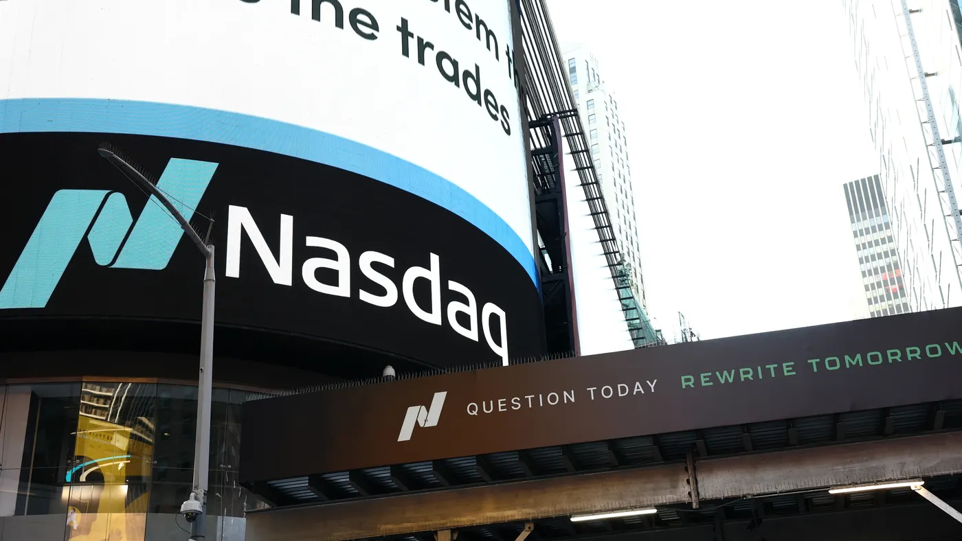 Nasdaq logo and signage on the curved exterior of its MarketSite building, viewed from street level.