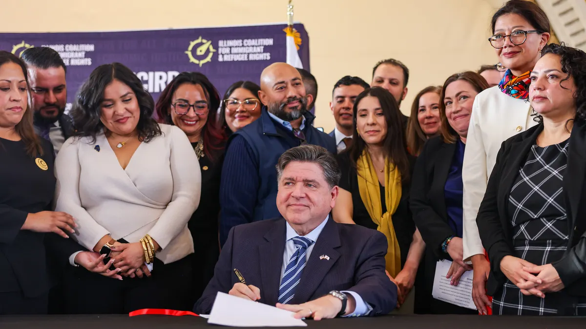 A person sits at a table surrounded by other people.