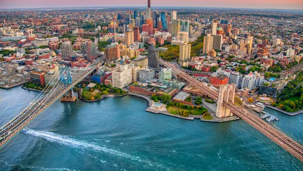An aerial shot shows the convergence of the Brooklyn and Manhattan Bridges in New York City.