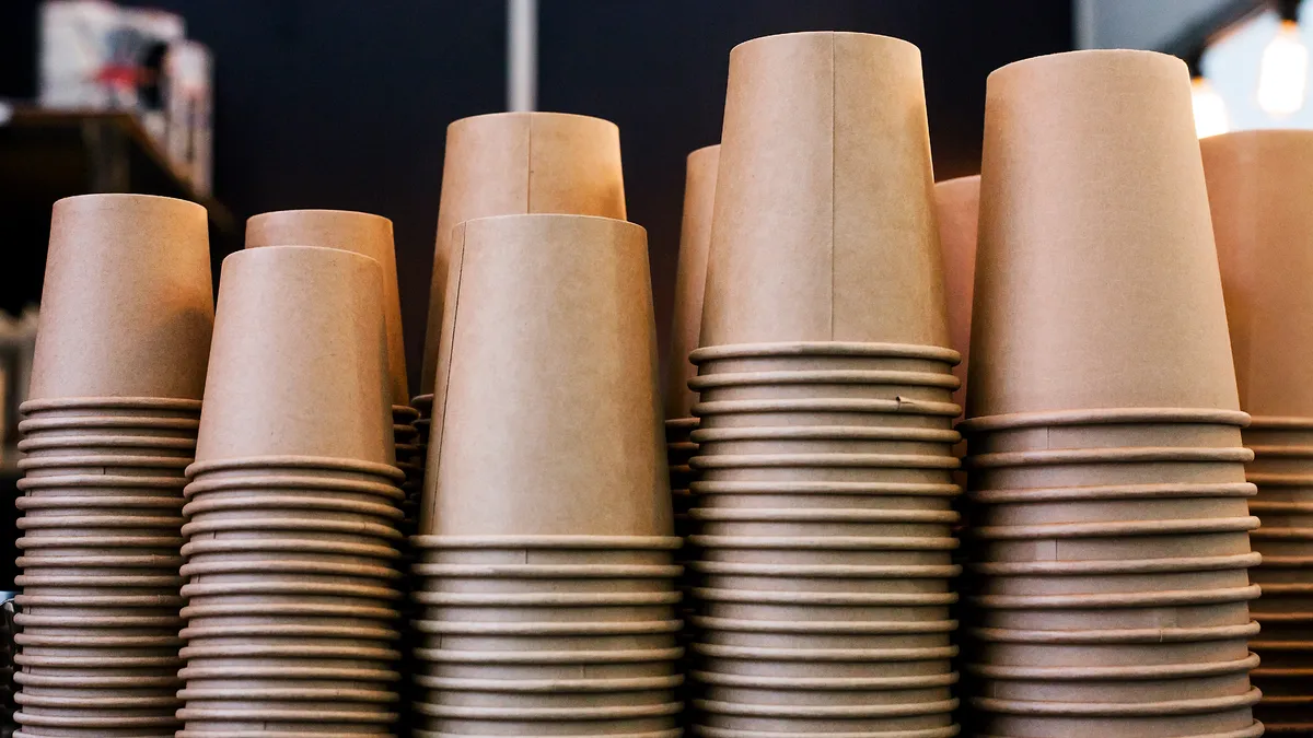 stacks of brown paper cups in a row in a coffeeshop setting