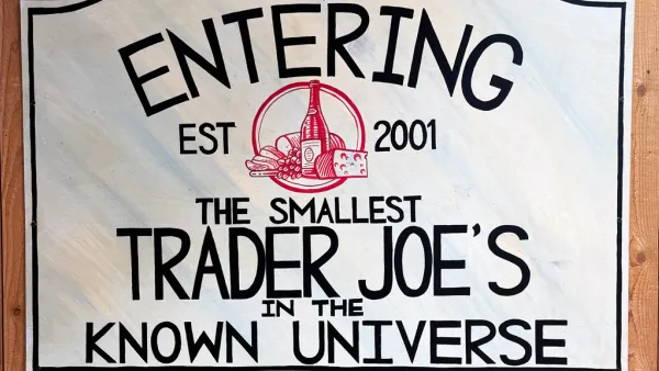 Sign that reads "Entering the Smallest Trader Joe's in the Known Universe" in black lettering on a while sign with a red logo in the middle