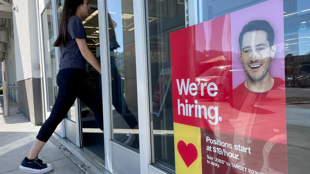 A customer walks by a now hiring sign posted in front of Target store