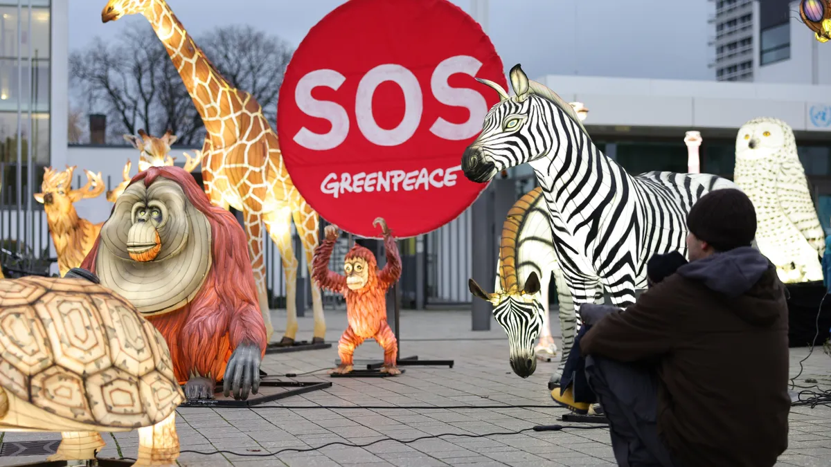 People walk past illuminated effigies of animals