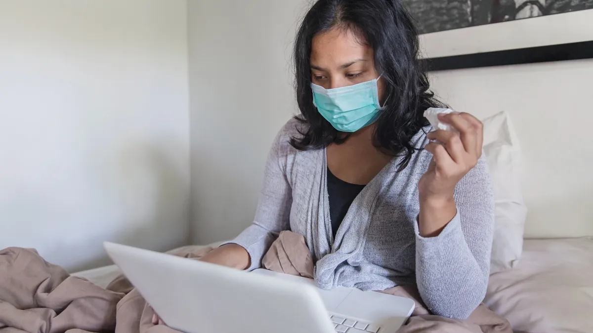 Cropped shot of sick businesswoman sending email to her employee from her bedroom during Coronavirus quarantine.