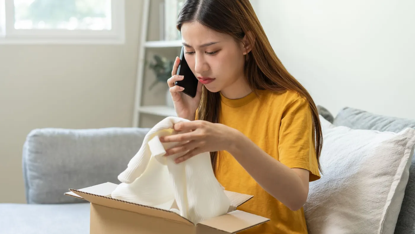 Person opening clothing order package while on the phone