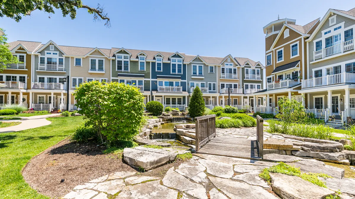 Brown, tree-level apartment community with stone walkway and grass in the foreground