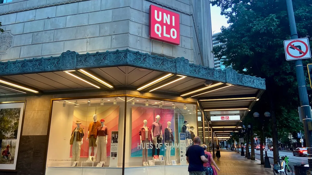 People walking past a clothing store window.