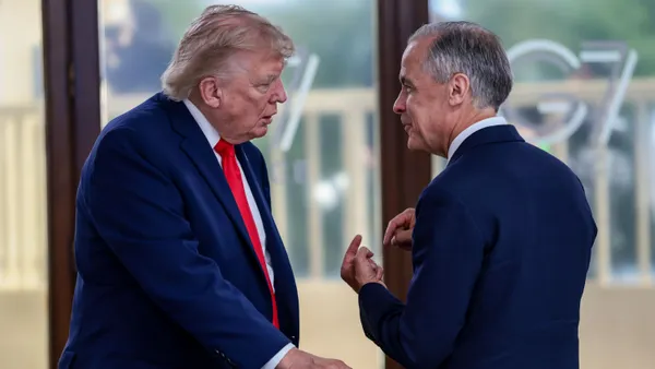 U.S. President Donald Trump puts his right hand on a chair while speaking to Canada Prime Minister Mark Carney.